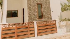 Ein modernes, zweistöckiges Haus mit Natursteinfassade, großen Fenstern und einem Holztor.