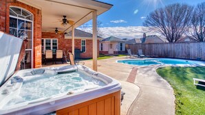 Een achtertuin met een jacuzzi, een zwembad en een terras met tuinmeubilair.
