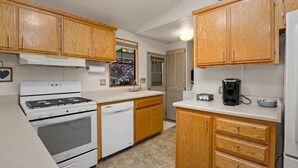A kitchen with wooden cabinets, a white stove, a dishwasher, and a coffee maker.