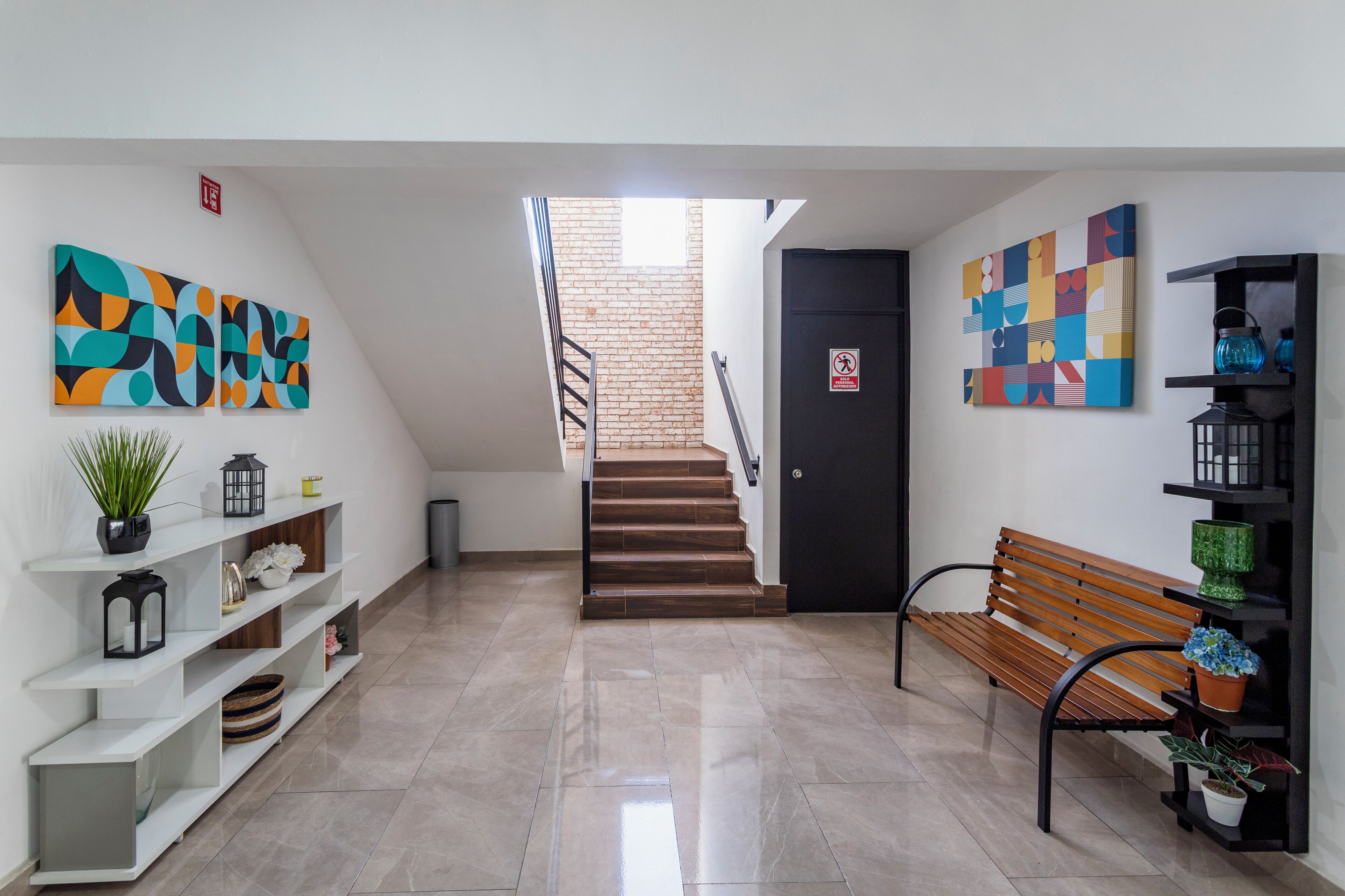 A modern interior with a staircase, a bench, and wall art.
