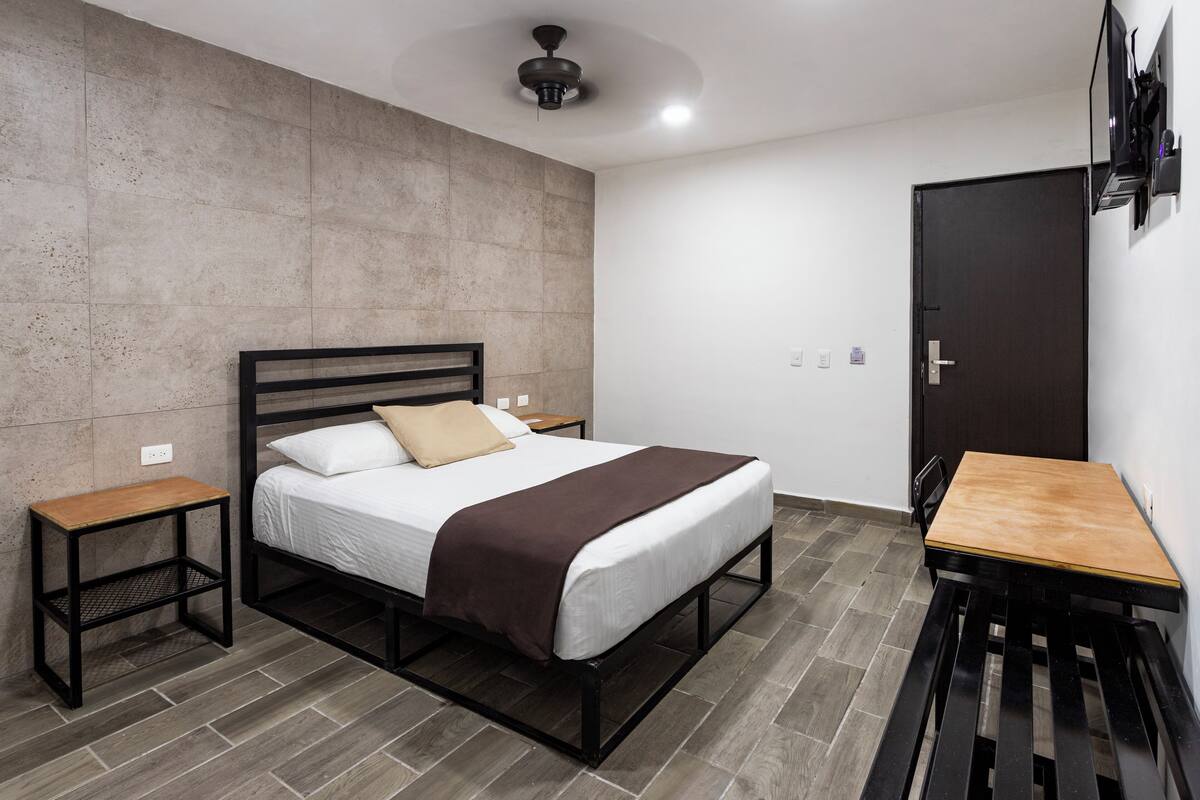 A modern bedroom with a bed, bedside tables, a desk, and a wardrobe.