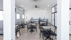 Un espace repas moderne doté de plusieurs tables et chaises, de ventilateurs de plafond et d’un éclairage encastré.