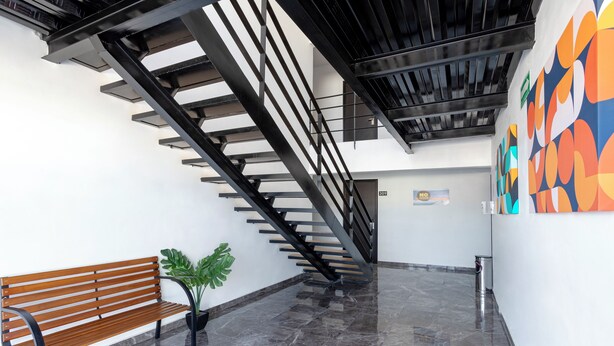 Un intérieur moderne avec un banc en bois, un escalier et une fresque murale colorée.