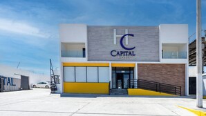 Un hôtel moderne, reconnaissable à son panneau « Capital Hotel » bien visible, à son entrée sécurisée par un portail et à son espace de stationnement.