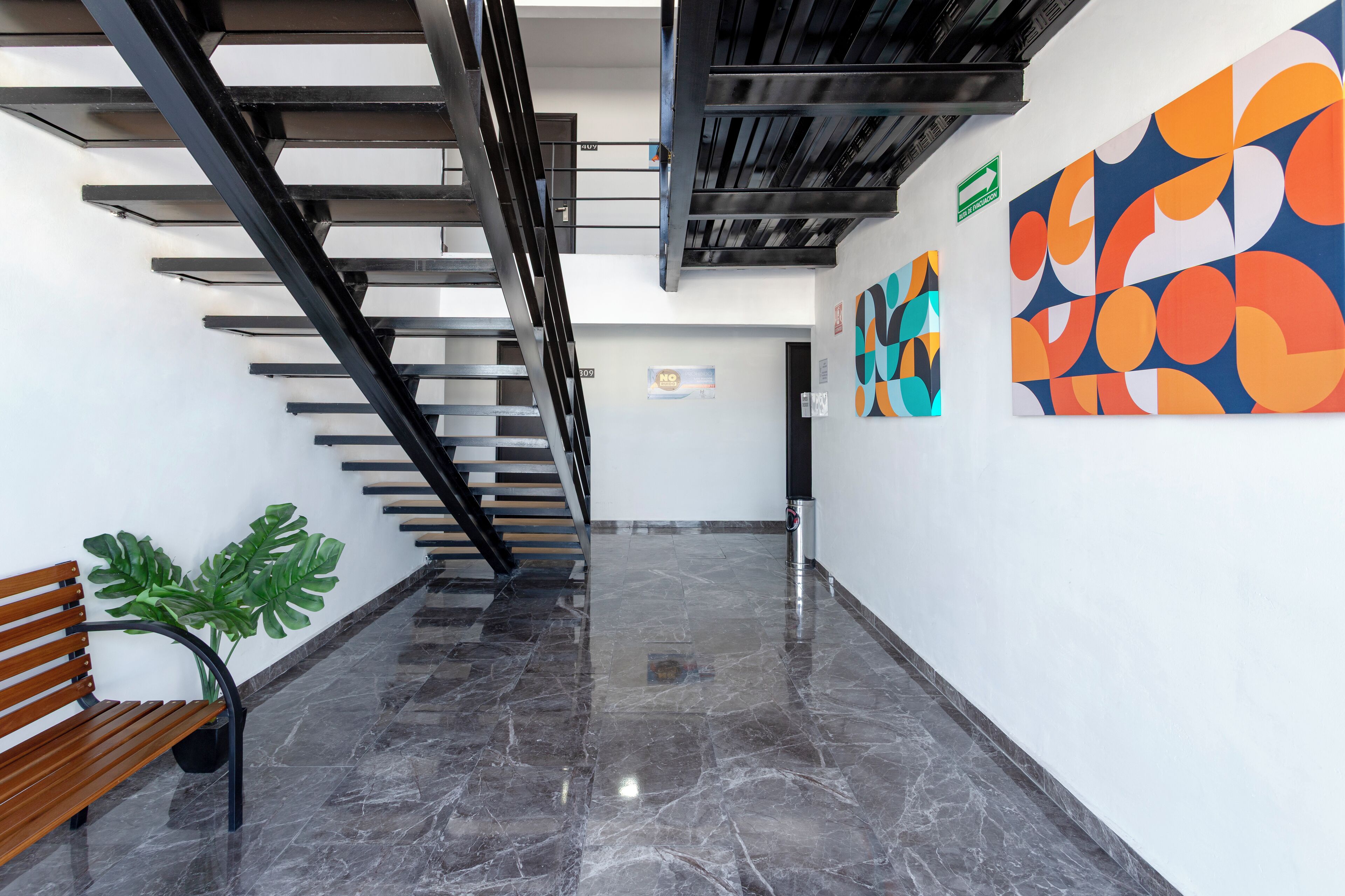 A modern interior with a staircase, a bench, and abstract art on the walls.