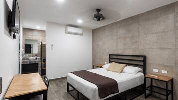 Un dormitorio moderno con cama, mesitas de noche, un escritorio y una televisión.
