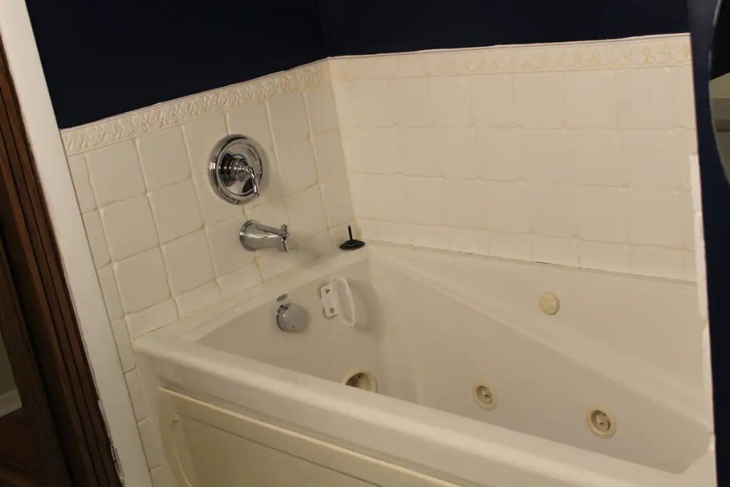 Un baño en esquina con una bañera blanca, un grifo cromado y un pequeño jabonero blanco.