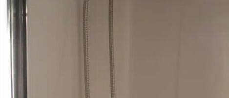 A shower with a handheld showerhead and a wall-mounted faucet.