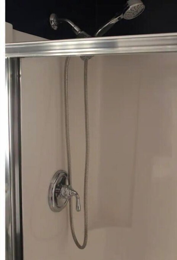 Une douche équipée d’un pommeau de douche à main et d’un robinet fixé au mur.