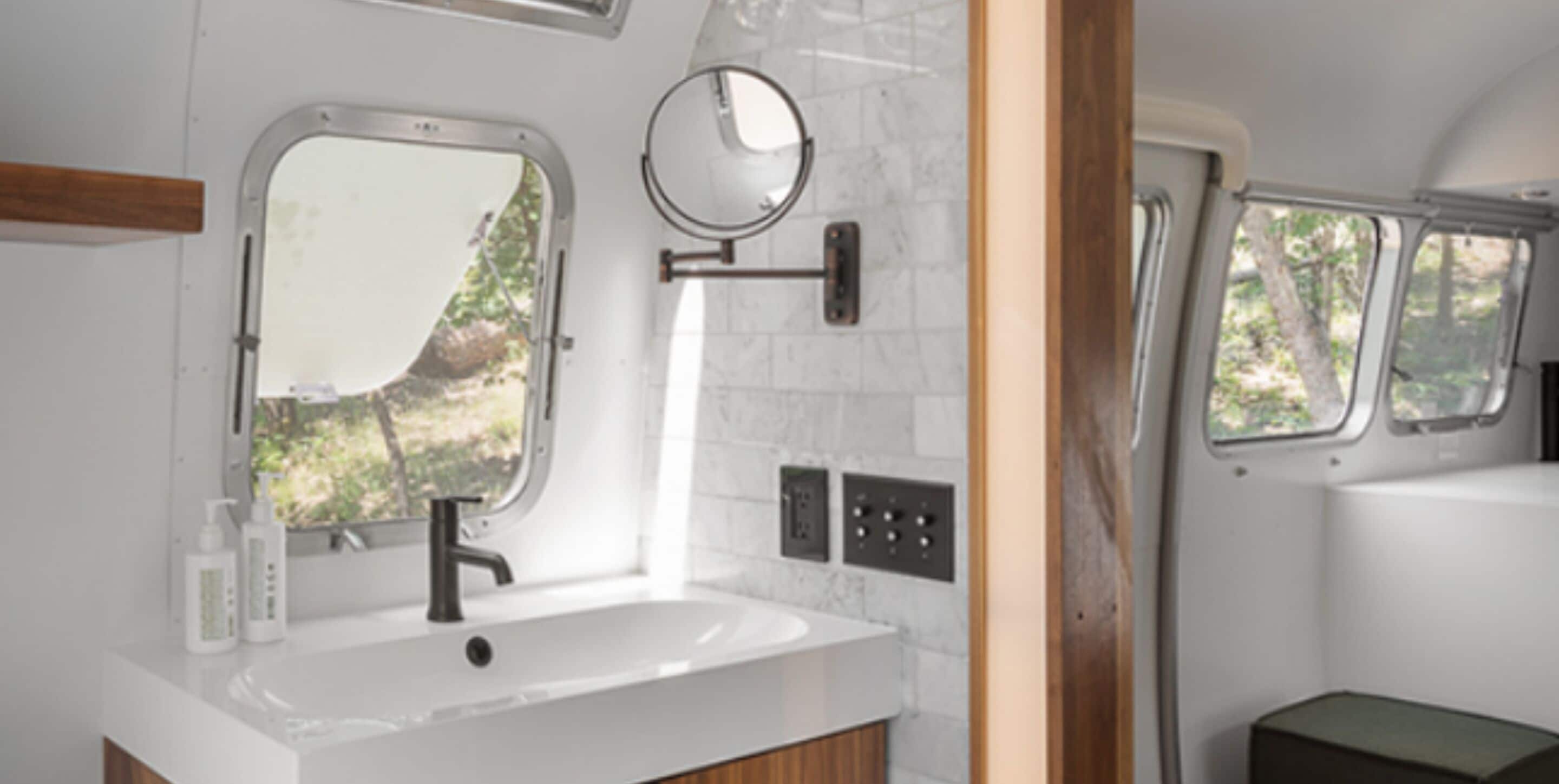 A bathroom with a white sink, a mirror, and a window.