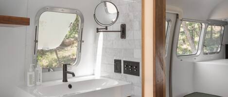 A bathroom with a white sink, a mirror, and a window.