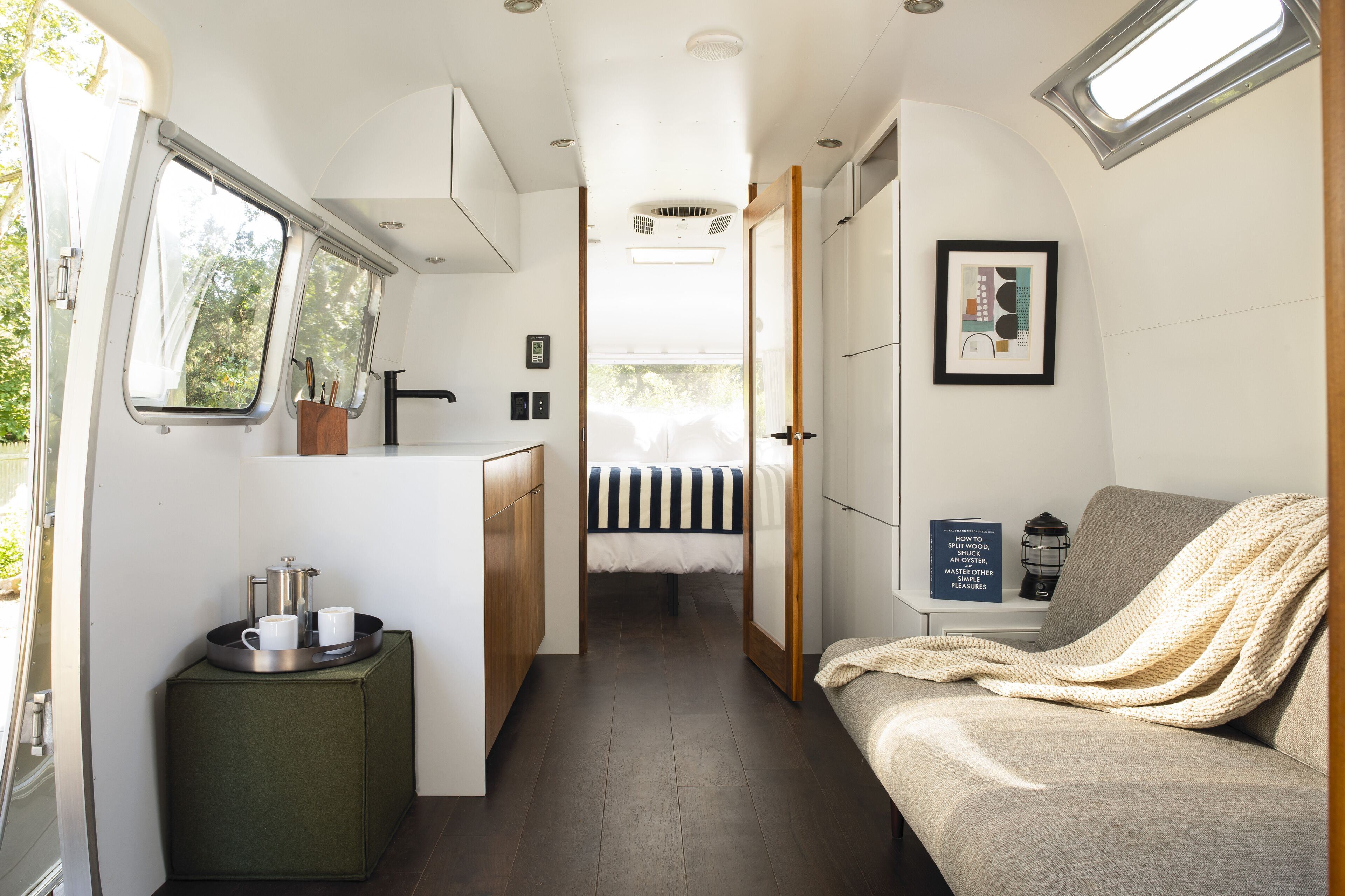 Un intérieur de camping-car compact comprenant un coin cuisine, un lit et un espace salon.