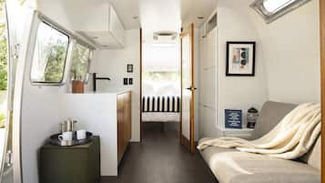 Un intérieur de camping-car compact comprenant un coin cuisine, un lit et un espace salon.