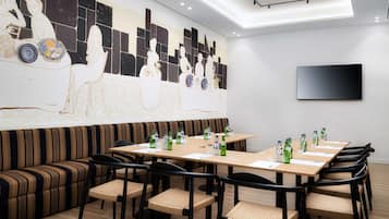 Una sala de conferencias moderna con una mesa larga, sillas, un sofá y un gran mural abstracto en la pared.