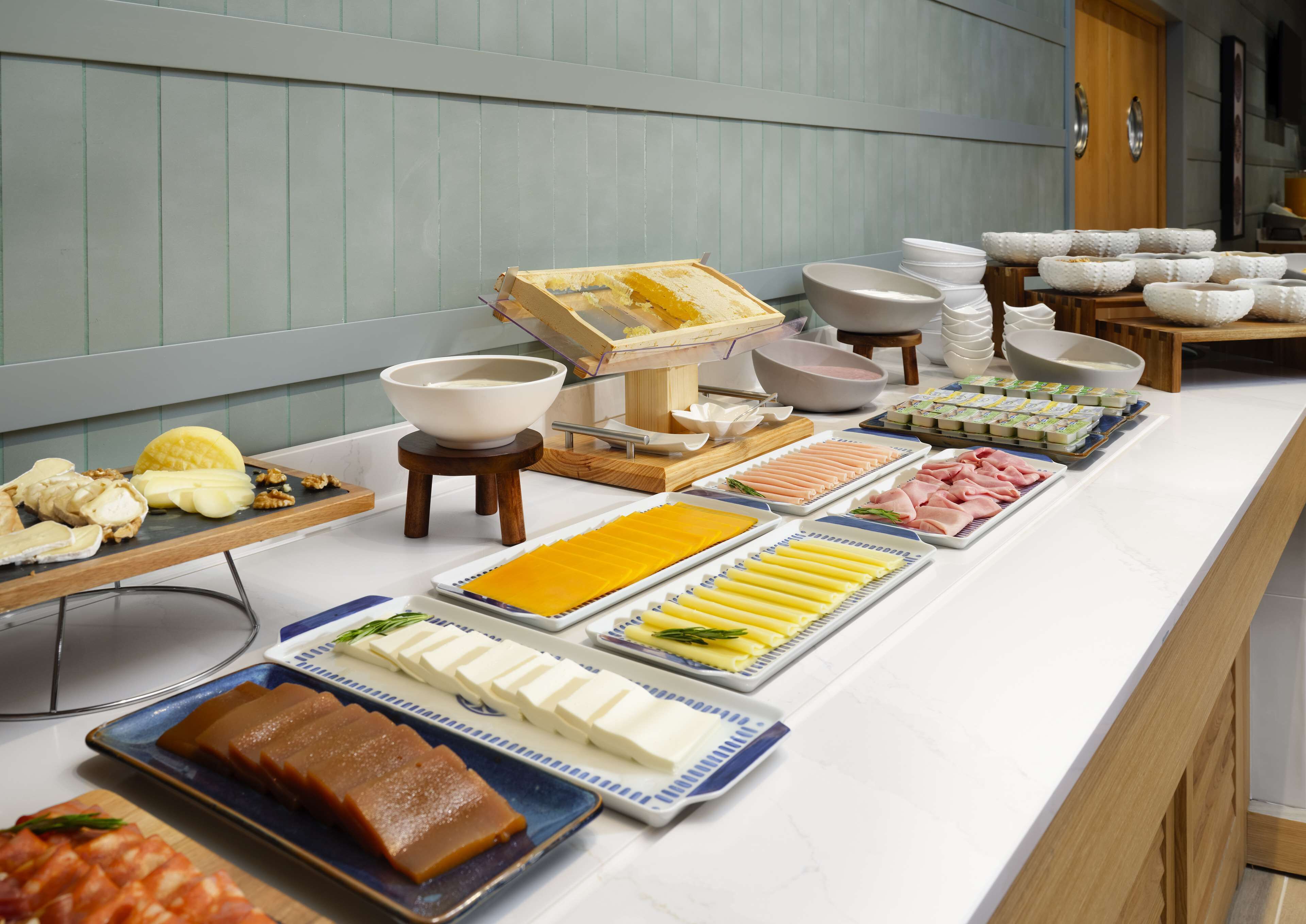 A buffet with various food items including meats, cheeses, and fruits.