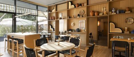 A modern dining area with wooden furniture, a round table, and shelves with decorative items.