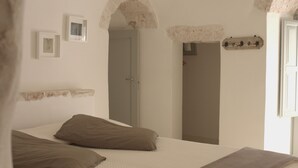 Un dormitorio con cama, almohadas, una puerta y un estante con fotografías.
