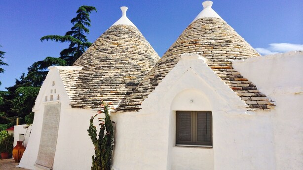 Un edificio tradicional con techo de piedra, una ventana pequeña y una puerta.