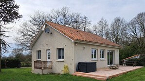 A single-story house with a tiled roof, a small porch, and a covered patio area. -  Holiday home with lake and grounds for families and groups. (L'Auvergneuse, Fenery)