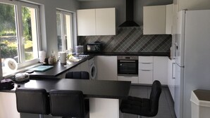 A modern kitchen with a central island, built-in oven, and a large window providing natural light. -  Holiday home with lake and grounds for families and groups. (L'Auvergneuse, Fenery)