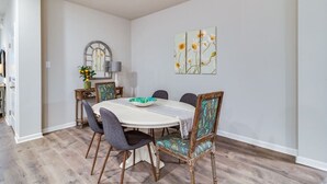 A dining area with a round table, chairs, and a vase of flowers.