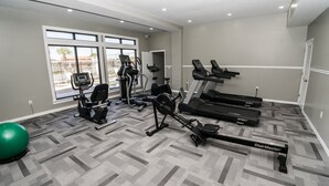 Un gimnasio con cintas de correr, bicicletas estáticas y una pelota de ejercicio.