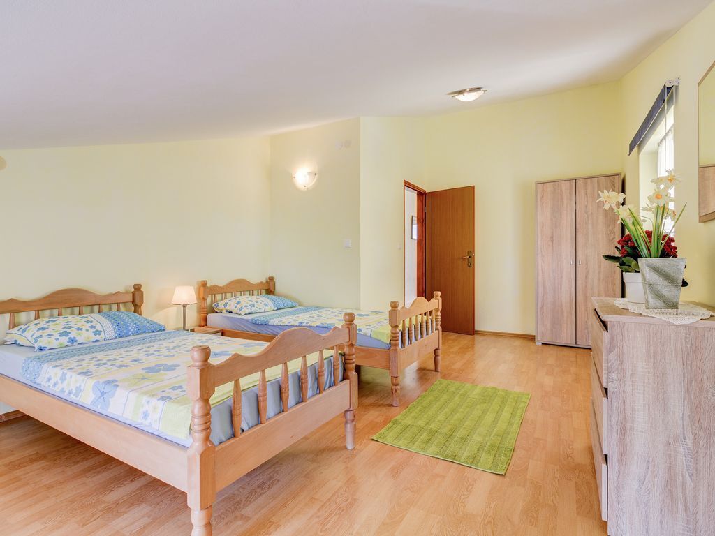 Une chambre à coucher avec deux lits en bois, un tapis vert, une armoire en bois et un miroir au mur.