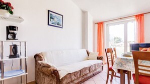 A living room with a sofa, a coffee machine, a table with chairs, and a window with curtains. - Balcony with sea view, FAZANA, 280m to the main beach, 400m to the old town  (Fažana)