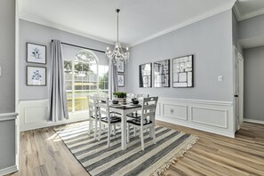 A dining room with a chandelier, a large window with curtains, and framed artwork on the walls. - Cozy & Quiet in Georgetown Pet-friendly & Long Stays (Georgetown)