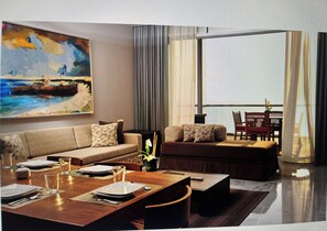 A modern living room with a sleeper sofa, dining table set for four, and three TVs. - Experience this resort!  Vidanta GrandMayan (Nuevo Vallarta)