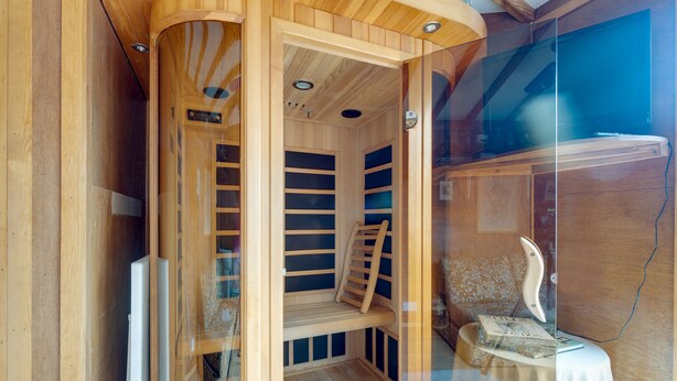 A sauna with wooden benches and a glass door, a small table with books, and a wooden ceiling. - Charming Historical Cottage in Scarborough (Scarborough)