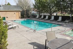 A swimming pool with lounge chairs and a table, surrounded by a fence and trees. - Idlewild Park condo by downtown + Pool & Parking (Reno)