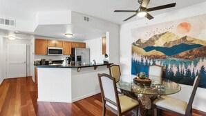 Una cocina moderna con armarios de madera, una isla central y un comedor con mesa y sillas de vidrio.