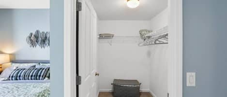A narrow hallway with a door leading to a bedroom, a small storage basket, and a wall-mounted shelf.