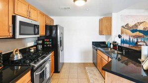 Una cocina con armarios de madera, un refrigerador de acero inoxidable, un microondas y una estufa a gas.