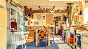 A cozy kitchen with a wooden dining table, chairs, and a vintage stove. - Family Country Cottage With a Private Valley View (Scarborough)