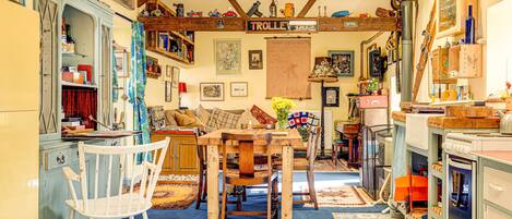 A cozy kitchen with a dining area, wooden furniture, and various kitchen appliances.