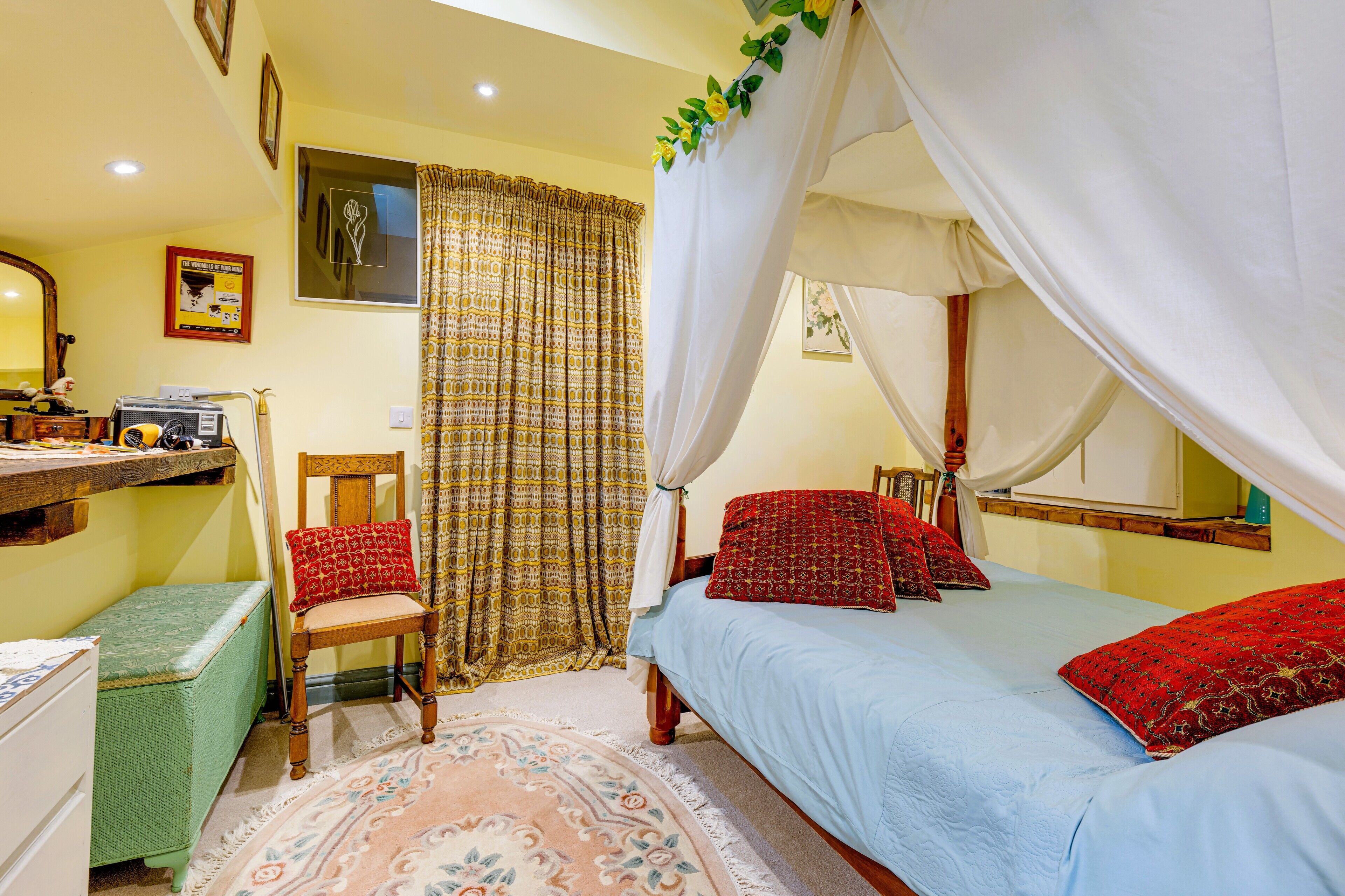 A bedroom with a bed, a chair, a desk, and a window with curtains.