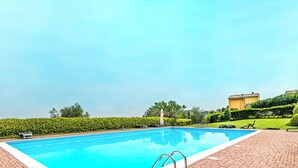 A rectangular swimming pool with a clear blue water surface, surrounded by a brick patio and a well-maintained hedge. - Poggio Picedo P1 32 by Wonderful Italy (Polpenazze del Garda)