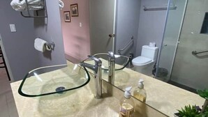 Een moderne badkamer met een glazen wastafel, een spiegel, een handdoekhouder en een toilet.