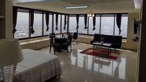 Una camera d'hotel moderna con un'ampia finestra, un letto, un'area ristorazione e un divano.