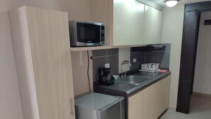 Una cucina compatta con forno a microonde, macchina del caffè e lavandino.