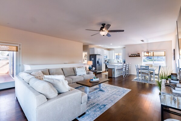 A modern living room with a sofa, coffee table, and a dining area with chairs and a table.