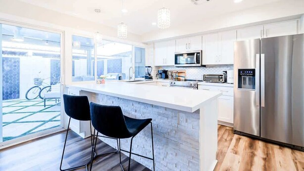 A modern kitchen with a large island, stainless steel appliances, and a view of a bicycle outside. - The Easy of Old Town - Luxury & Location! (Scottsdale)
