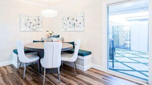 A dining area with a round table, white chairs, and two wall-mounted paintings. - The Easy of Old Town - Luxury & Location! (Scottsdale)