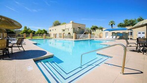A swimming pool with lounge chairs and umbrellas, surrounded by buildings with a clear sky. - The Easy of Old Town - Luxury & Location! (Scottsdale)