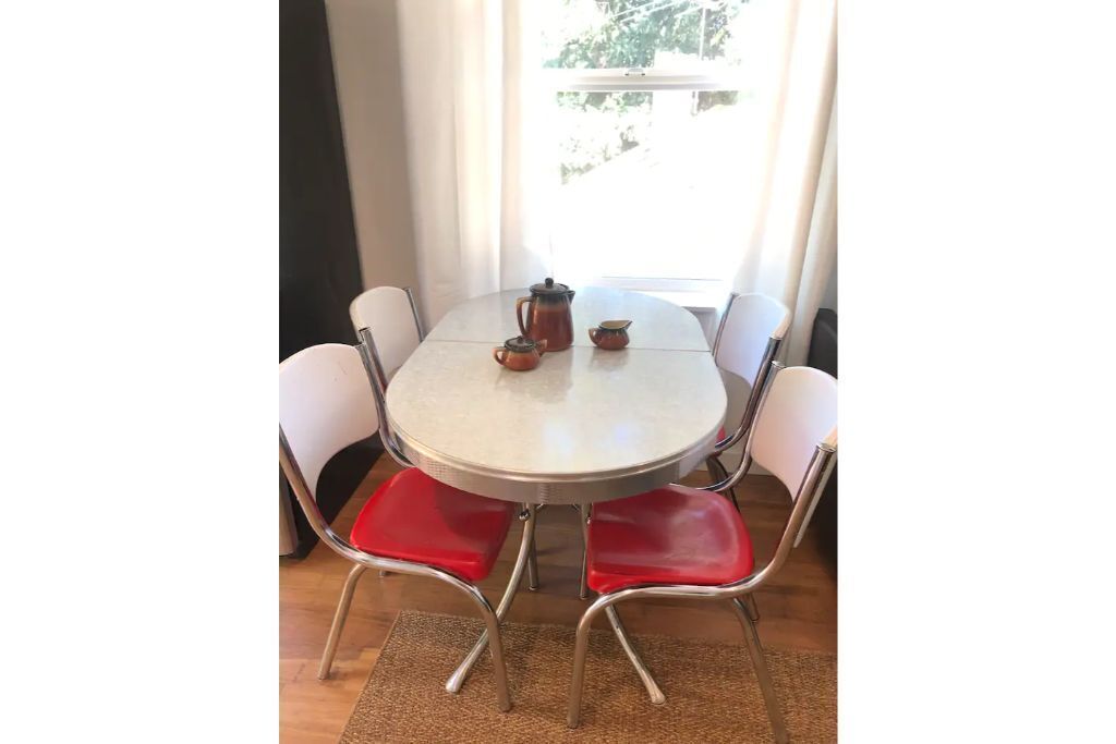 Une table ronde, quatre chaises rouges, une nappe blanche et un service à café.