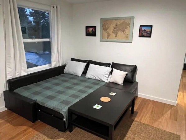 Un dormitorio con una cama, una mesita y una ventana.