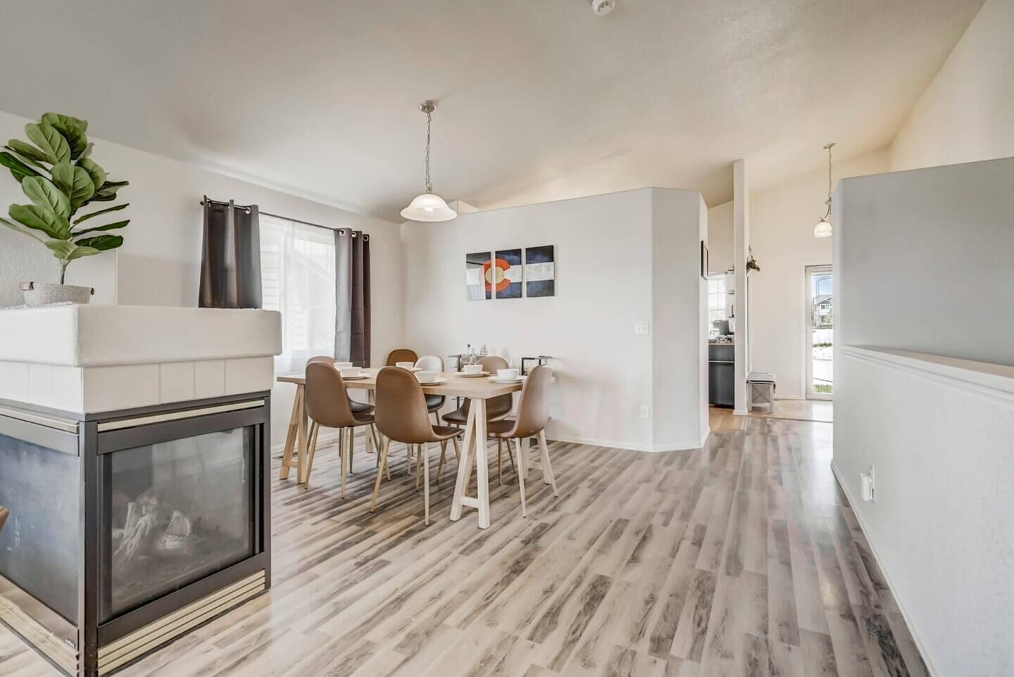 A modern kitchen with a dining area, featuring a large wooden table, chairs, and a fireplace.