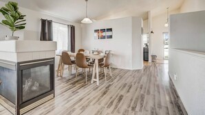 A modern kitchen with a dining area, featuring a large wooden table, chairs, and a fireplace.